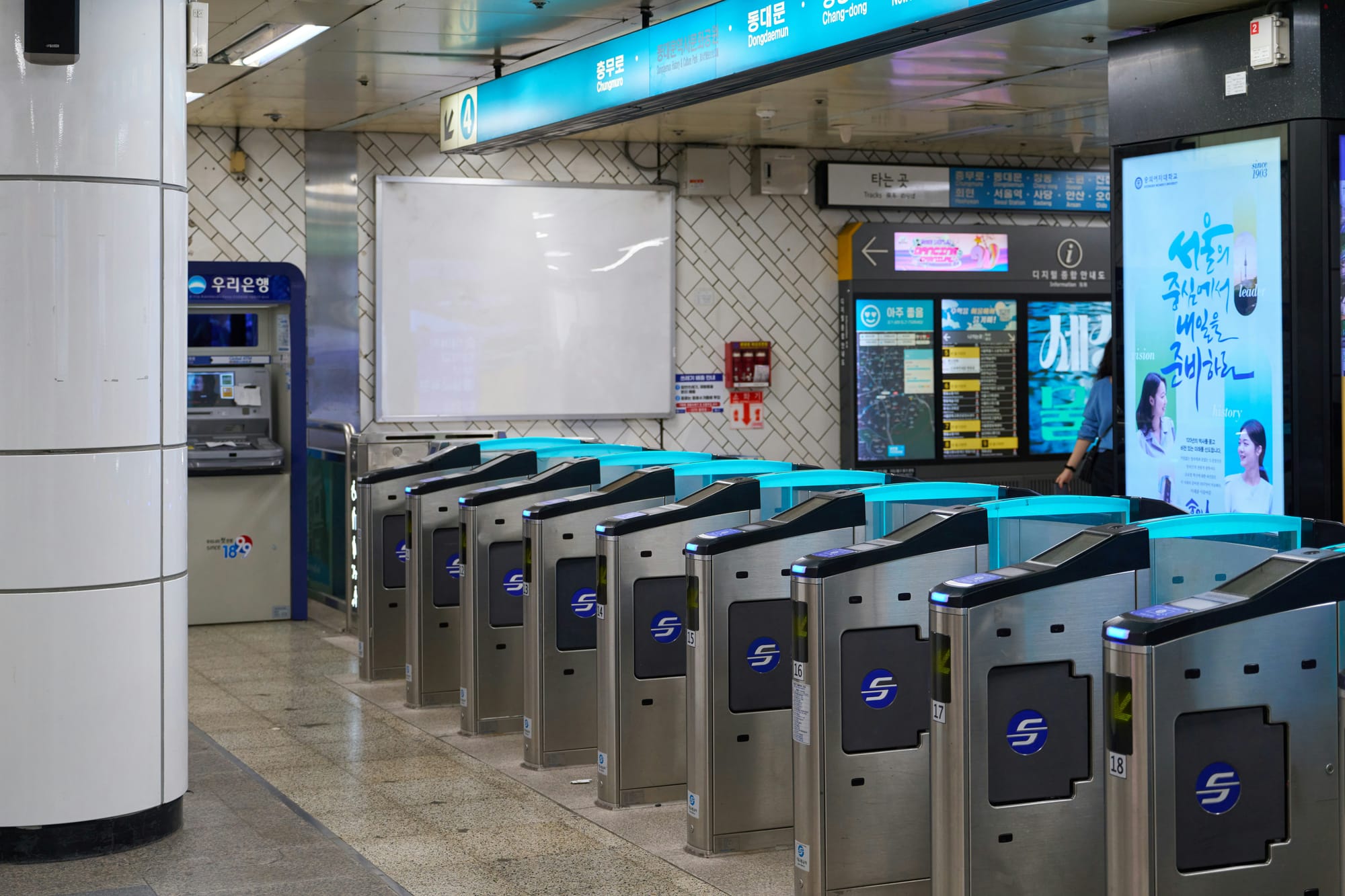 Fileira de catracas de estação de metrô vista de frente, com os corredores de passagem vazios.