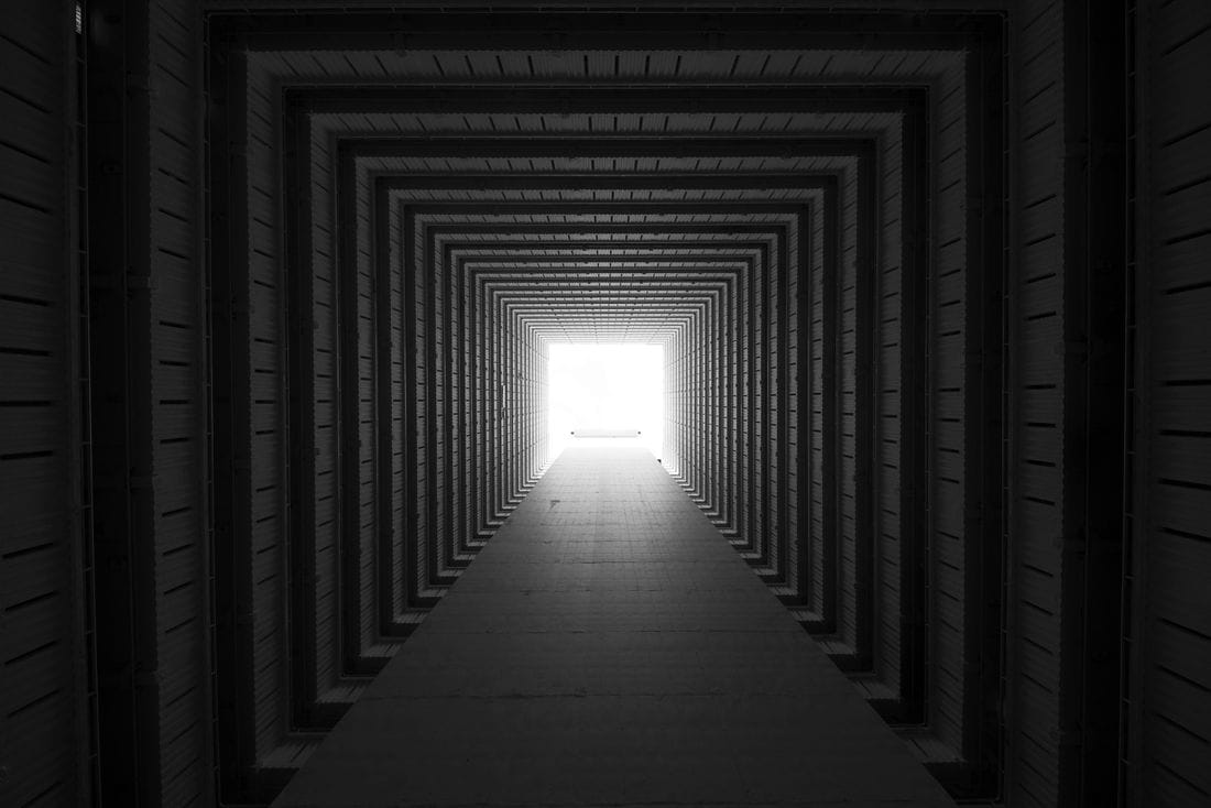 Uma passagem longa e escura, com a luz da saída no fim.